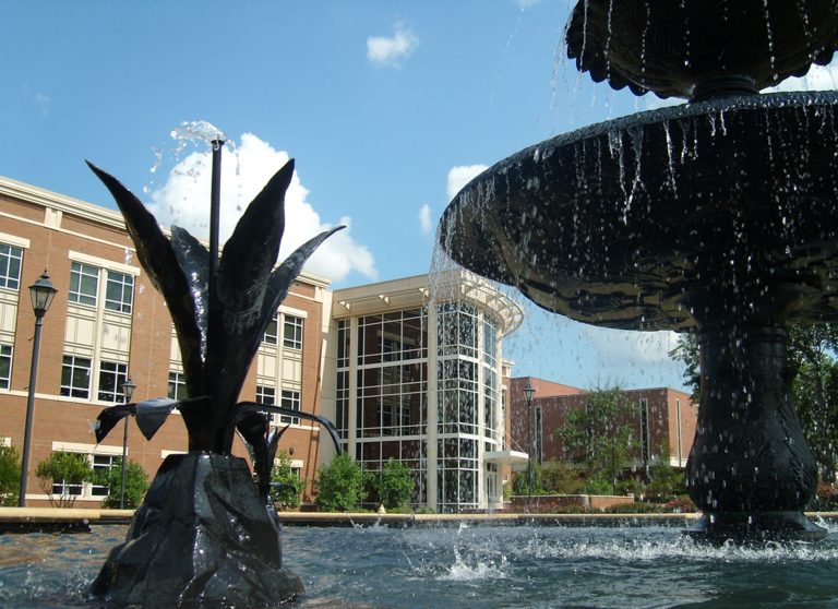 University Hall is seen in the background of a fountain on the Summerville Campus
