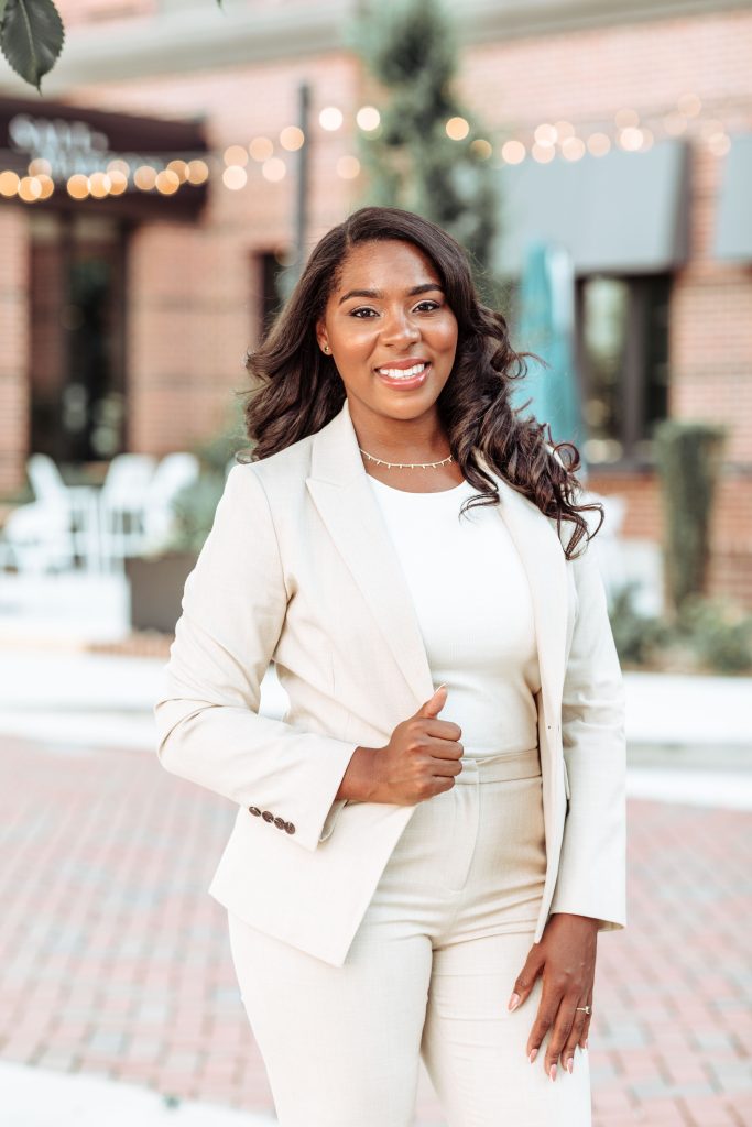 A woman posed and smiling at the camera in a pant suit