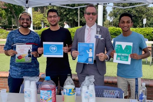 Three students and the Augusta University provost hold up cards