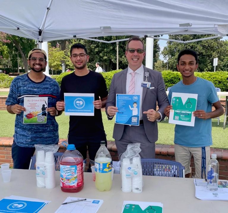 Three students and the Augusta University provost hold up cards