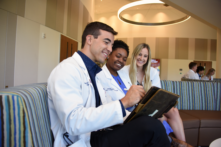 Three students from the Medical College of Georgia sitting inside the Ed Commons Building on the Health Sciences Campus.