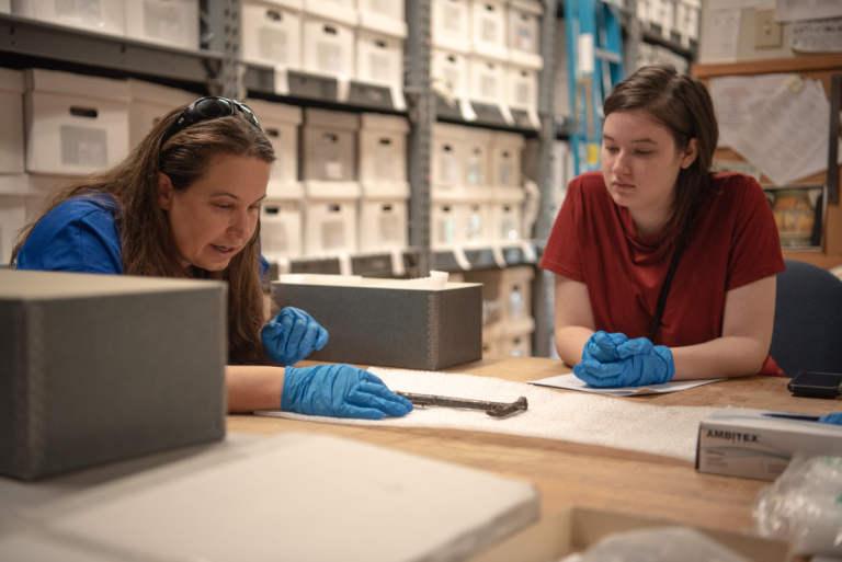 Professor and an intern working with artifacts.