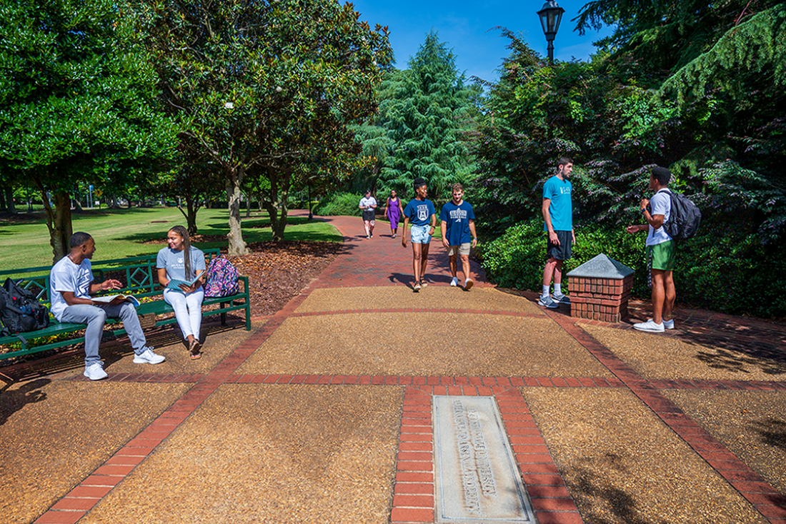 Augusta University students sitting and walking along the History Walk on the Summerville Campus.