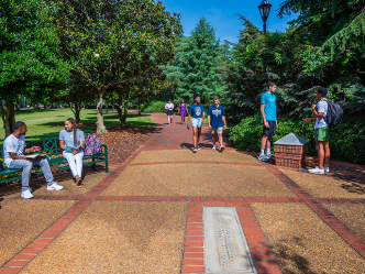 Augusta University students sitting and walking along the History Walk on the Summerville Campus.
