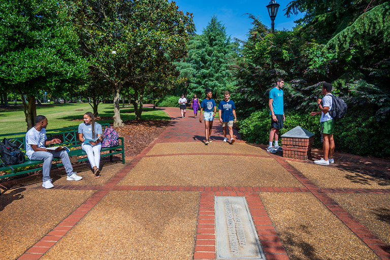 Augusta University students sitting and walking along the History Walk on the Summerville Campus.