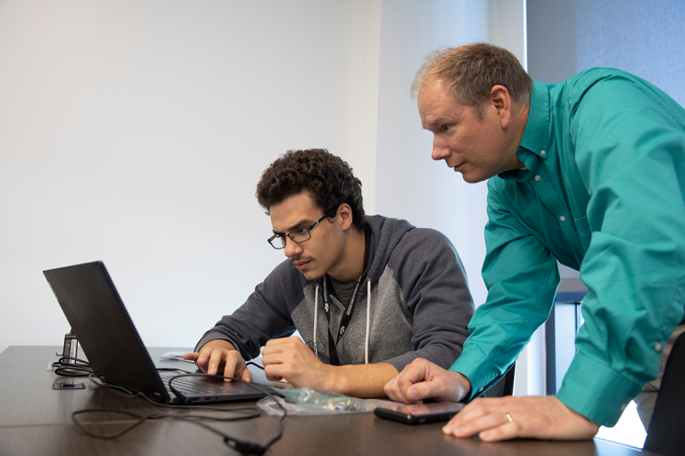 Professor leaning over to teach student on a computer