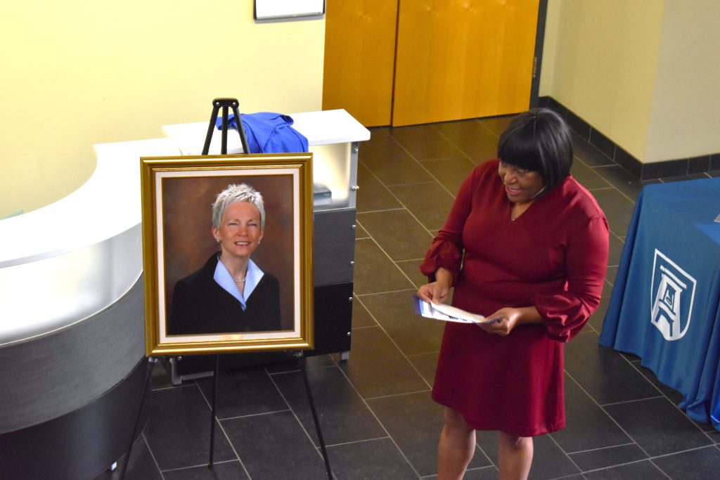 Melissa Johnson speaking in front of Dr. Marion's portrait.