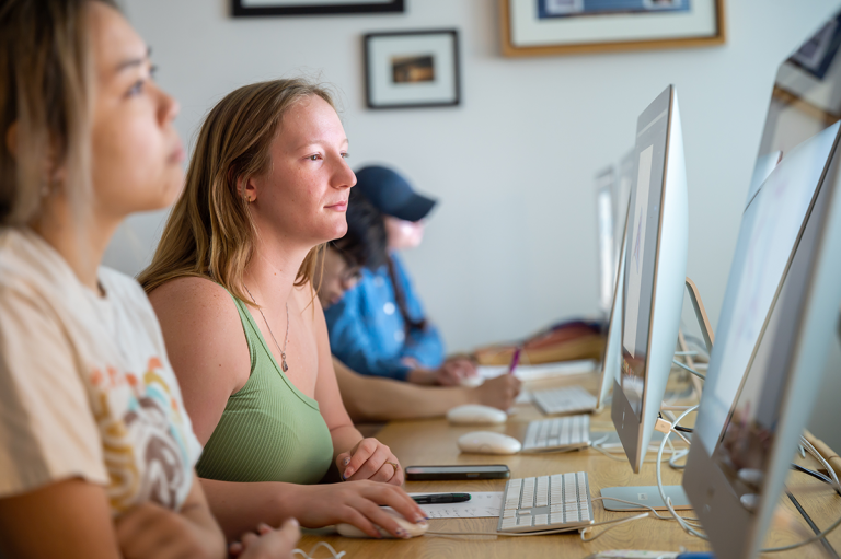 Three Augusta University students in a classoom with computers.