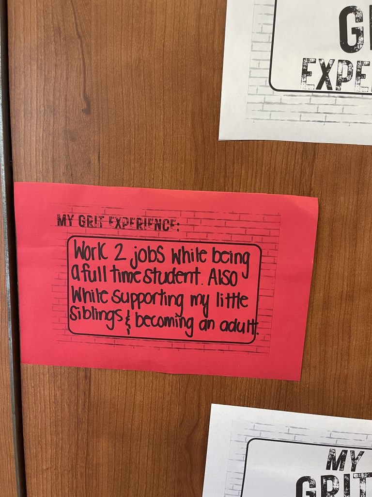 A red "brick" piece of paper that reads "work 2 jobs while being a full-time student. Also while supporting my little siblings/becoming an aunt.