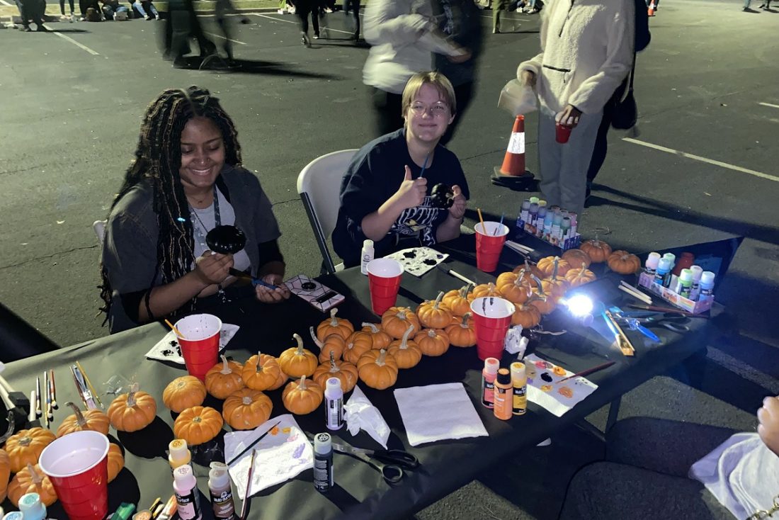 two students sitting at a table with pumpkins on it