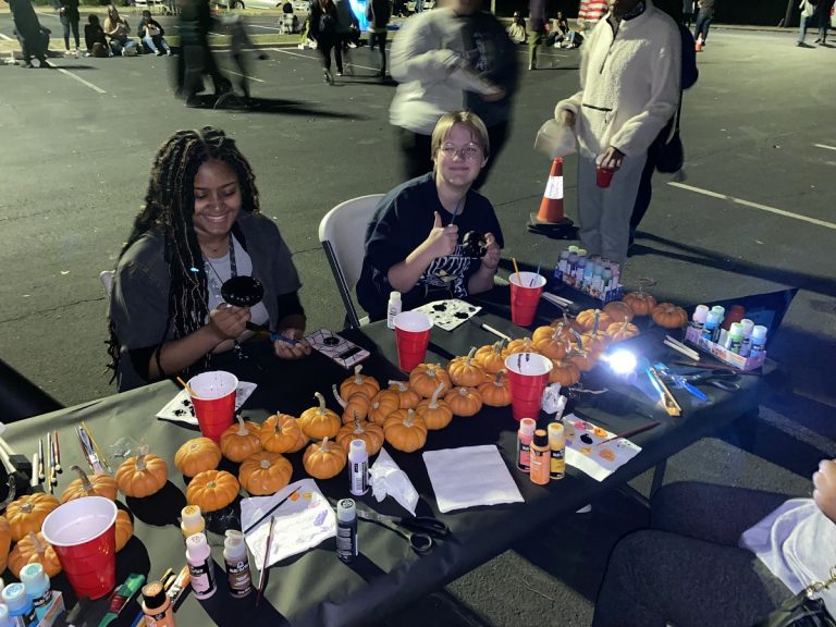 two students sitting at a table with pumpkins on it