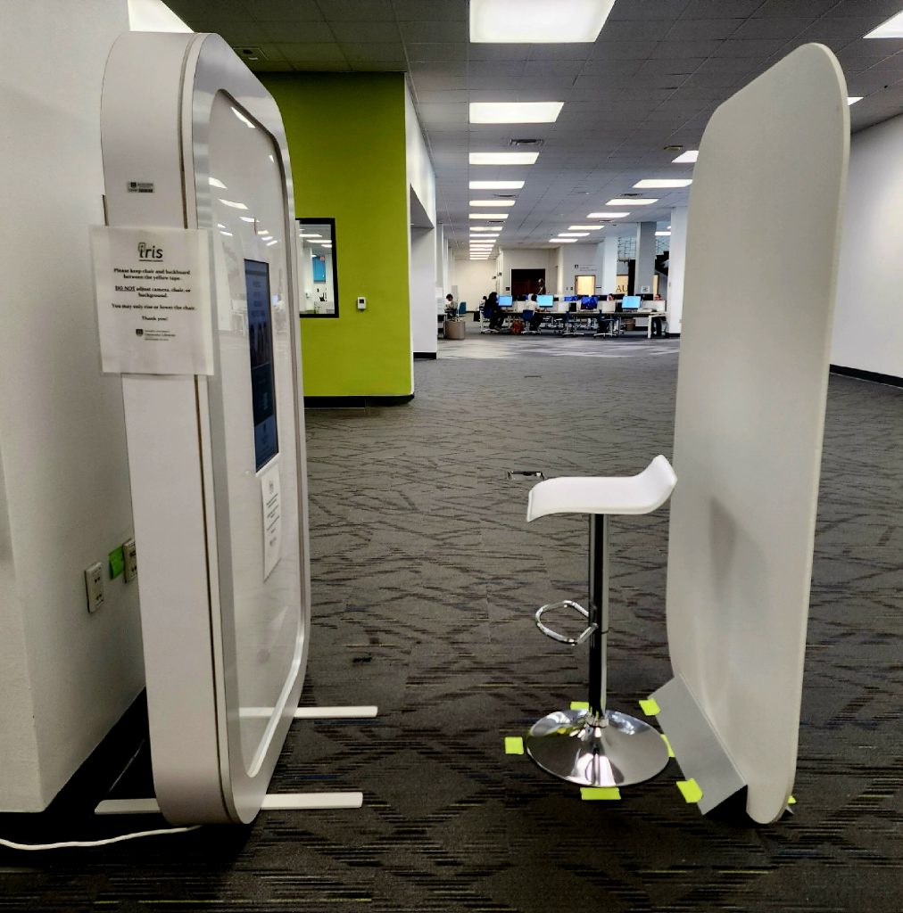 A photo booth is set up in a library with instructions for how to take head shots.