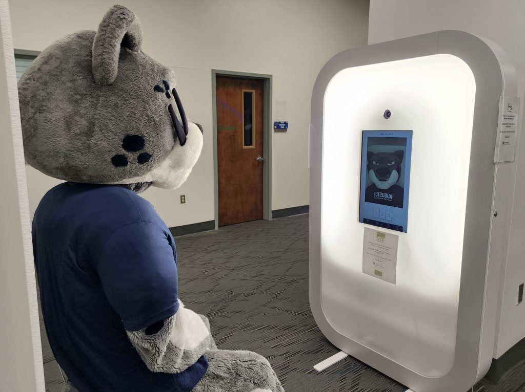 A college athletics jaguar mascot sits on a chair for a photo booth.