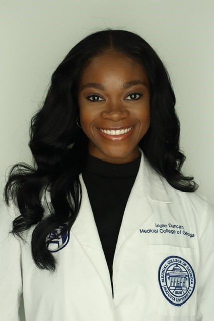 A female medical students poses for a photo wearing her official white coat.