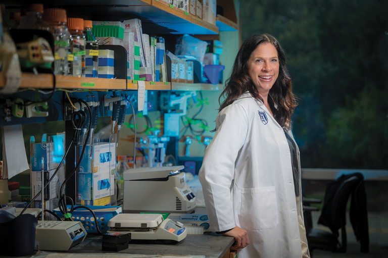 woman in a lab coat stands in a science lab