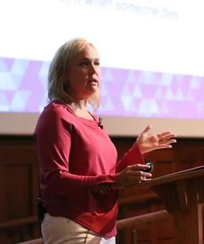 A woman stands at a podium and gives a presentation.