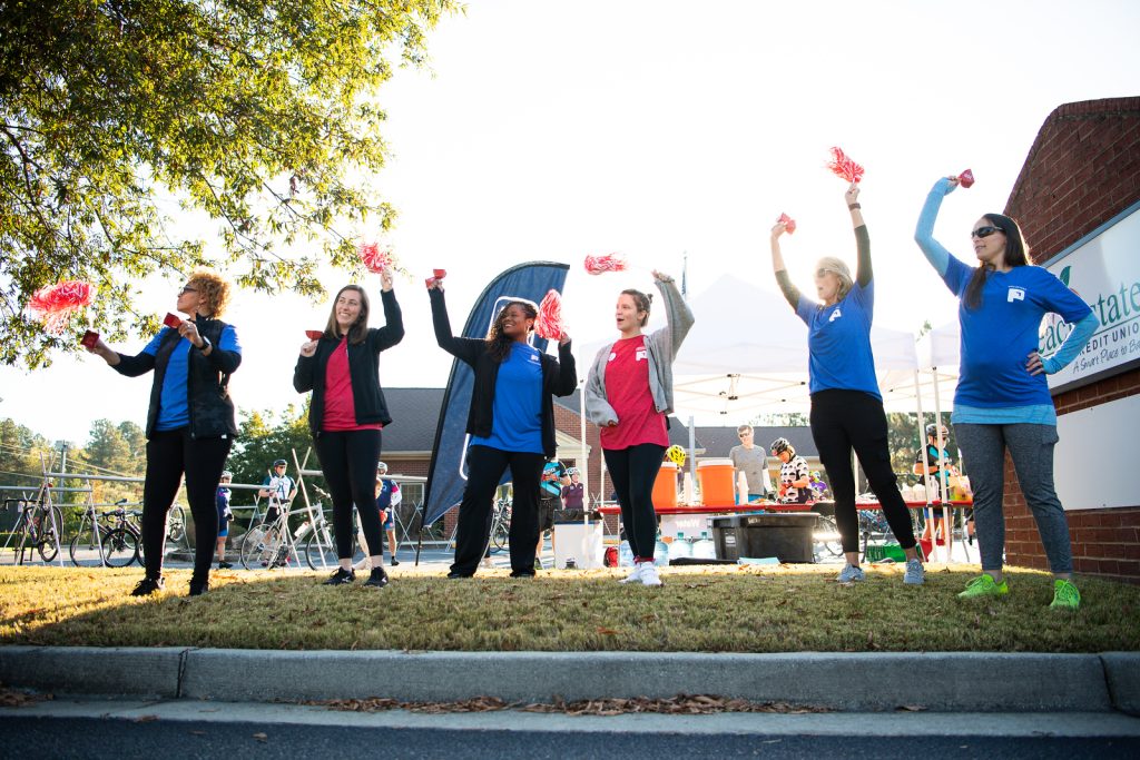 Group of people cheering on sidewalk.