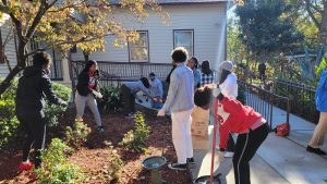 Young men and women help clean up around a building