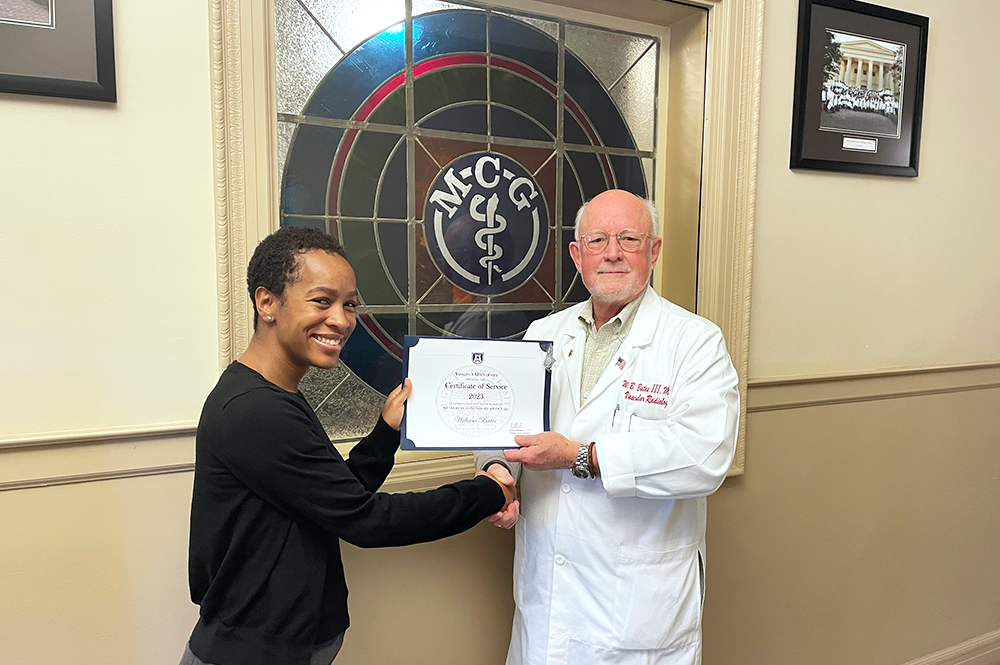 Two people stand together holding up certificate