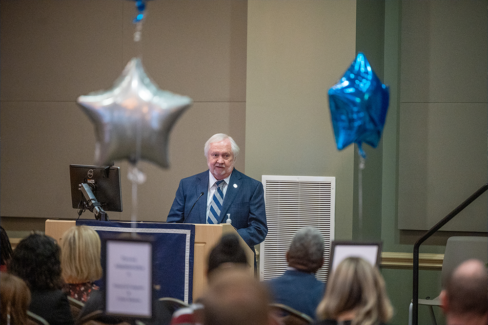 A man stands at a podium while giving a presentation.