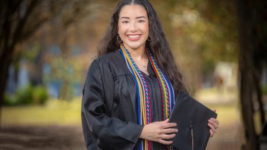 Woman smiling in graduation cap and gown