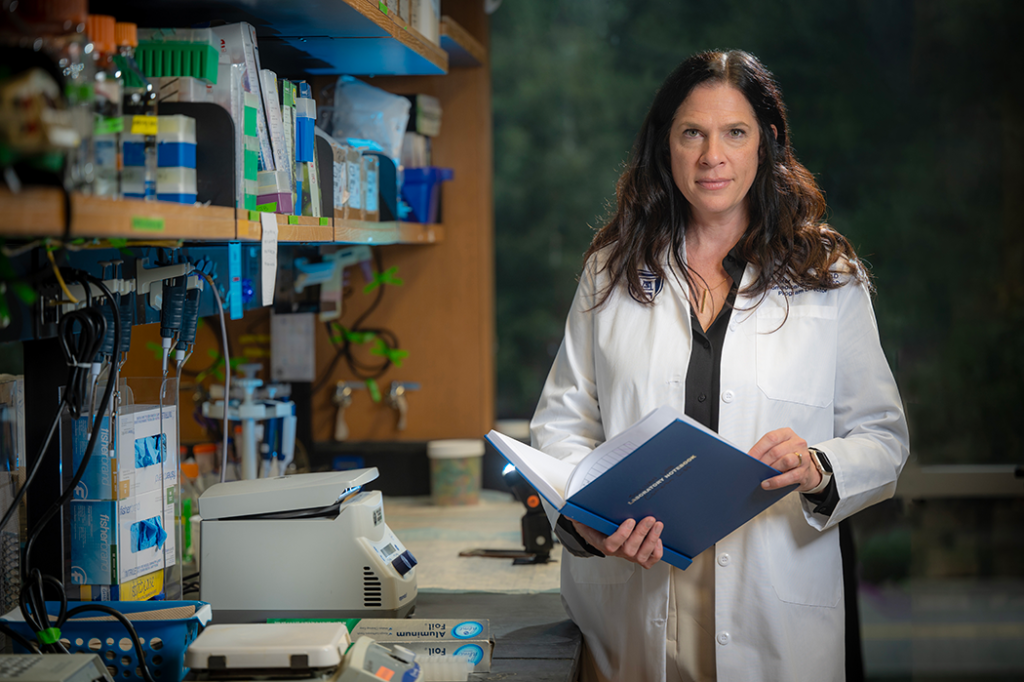 woman in a lab coat stands in a science lab