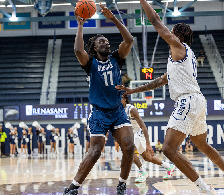 Man preparing to shoot a basketball over another man. 