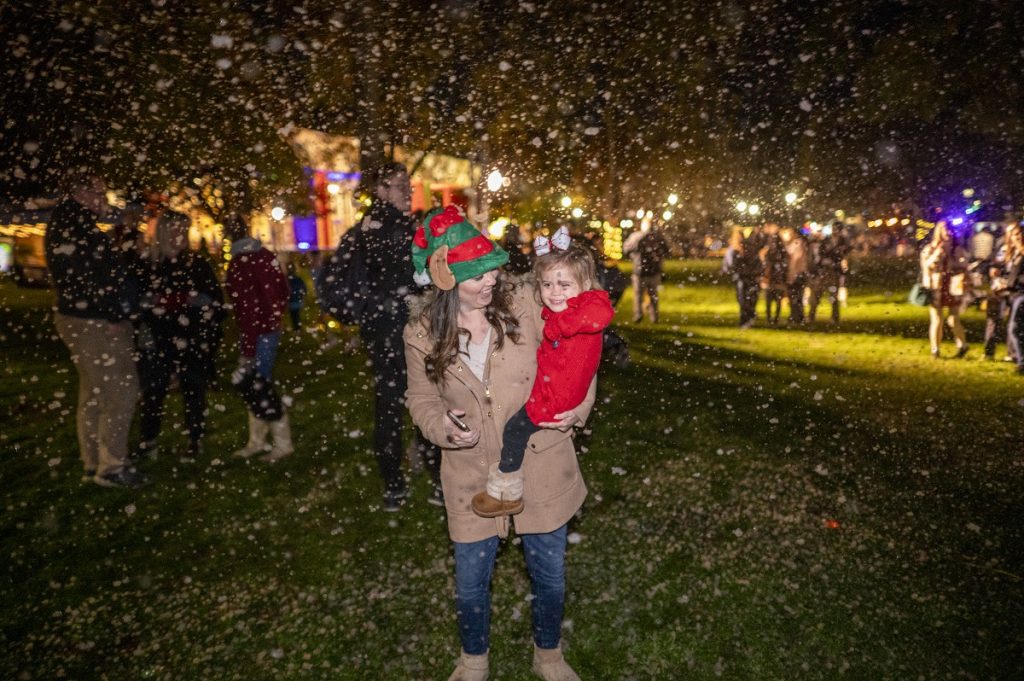 A woman holds a young child with "snow" falling around them