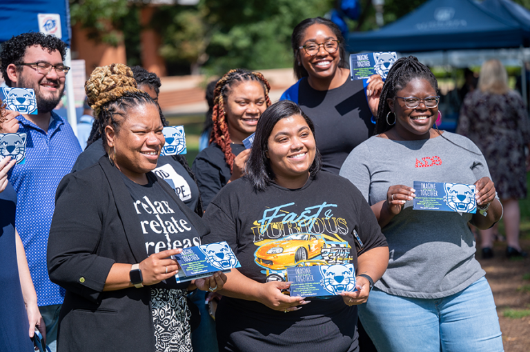 A group of women stand outside holding pledge cards for Augusta University's IGIVE campaign.