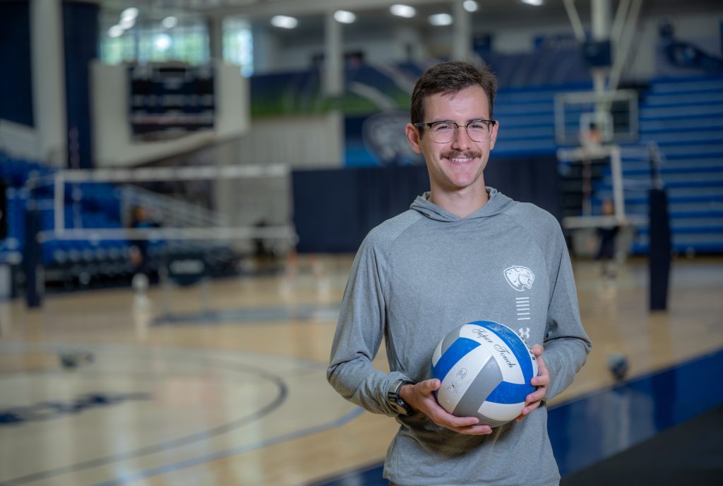 Man standing holding a volleyball. 