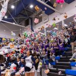 Students and cheerleaders throw stuffed animals onto a basketball court