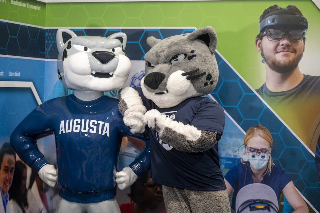 A college mascot depicting a jaguar stands with a statue of himself.