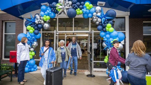 Students and their families move in to a dorm with a balloon arch over the doorways