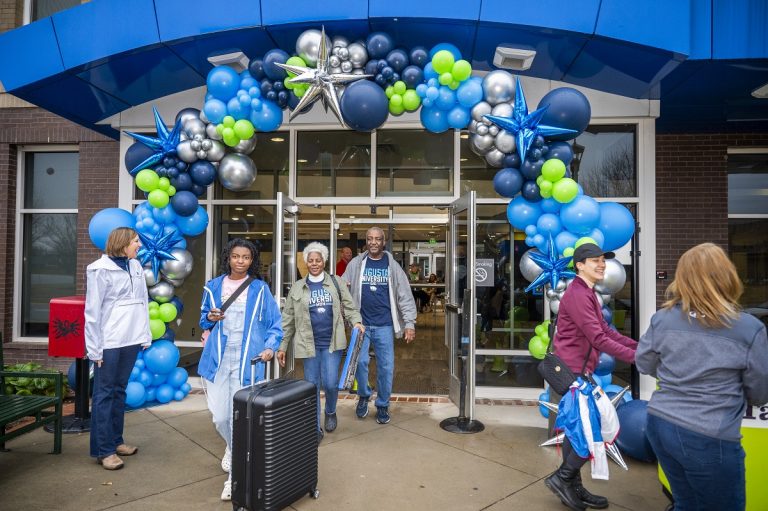 Students and their families move in to a dorm with a balloon arch over the doorways