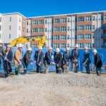 Men and women are part of a groundbreaking ceremony with shovels in hand