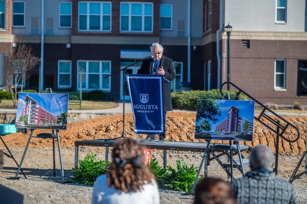 A man speaks at a podium at a groundbreaking event.