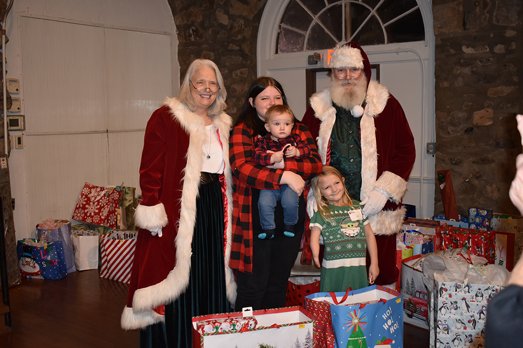 Santa and Mrs. Claus pose with a woman holding a small child while a young girl stands in front of her