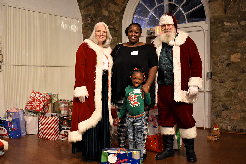 Santa and Mrs. Claus pose with a grandma and her granddaughter