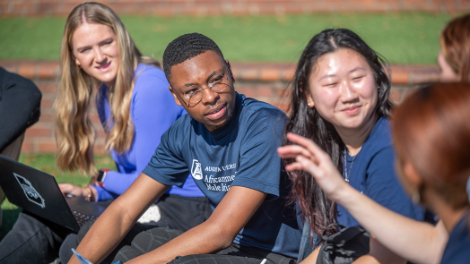 A group of students sitting outside on the Douglas Bernard Amphitheater on Augusta University's Summerville Campus