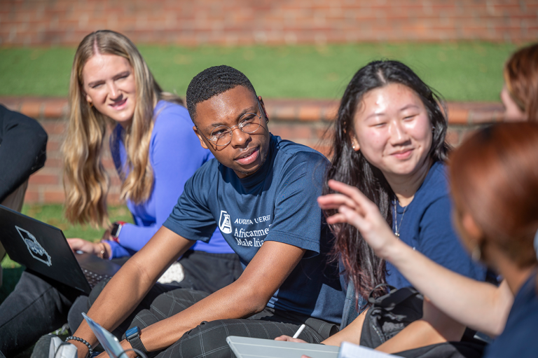 A group of students sitting outside on the Douglas Bernard Amphitheater on Augusta University's Summerville Campus