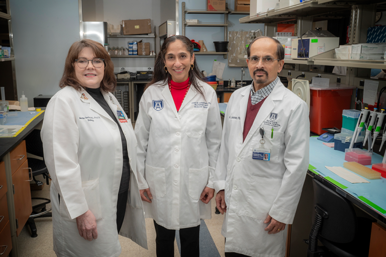 Three researchers, including two women and one man, stand in a lab and pose for a photo.