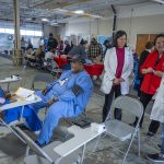 truck drivers sit at various stations with students and nurses and College of Nursing faculty members help them