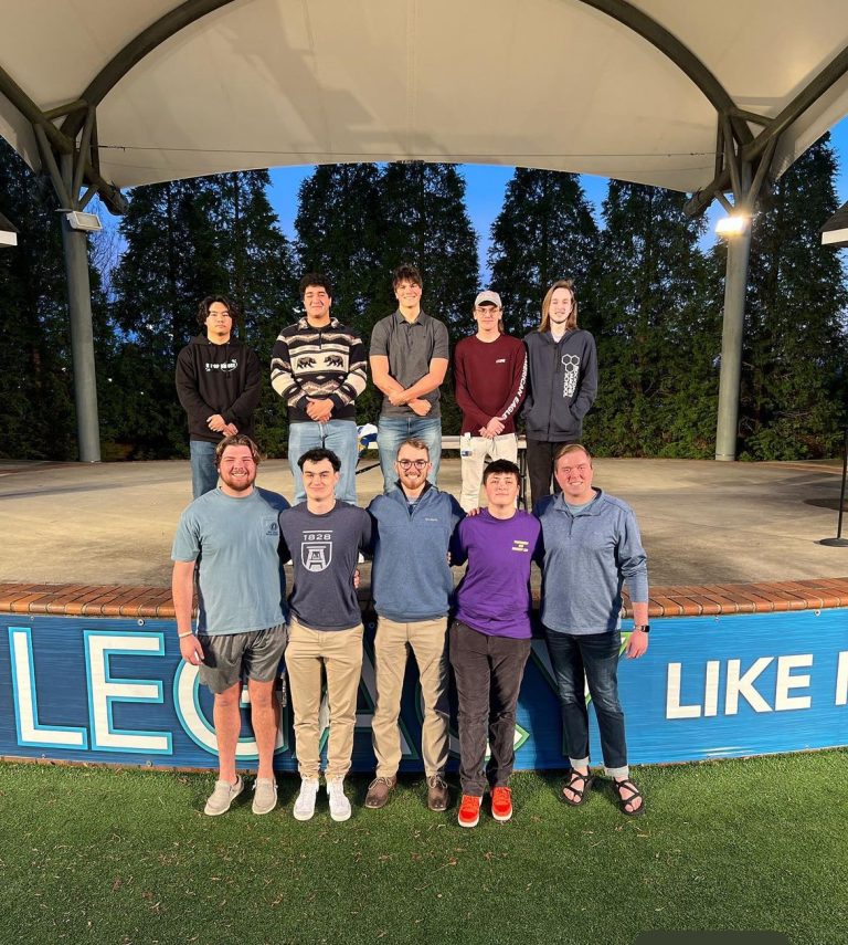 Young men stand and pose for a picture on an outside stage