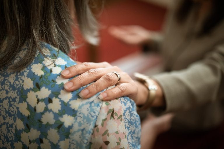 A person puts their hand on the shoulder of another