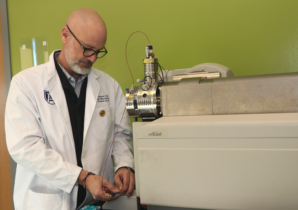 A man in a lab coat working with an NMR machine in a laboratory.