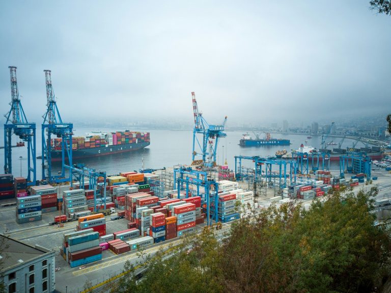 A container ship sits in a harbor with big cranes ready to unload it