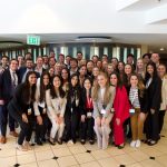 A few dozen people in business attire stand together for a group photo.