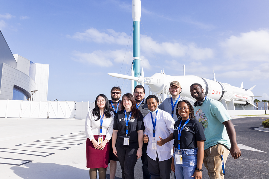 A group of college students gather for a photo in front of a rocket at NASA's Kennedy Space Center in Cape Canaveral, Florida.