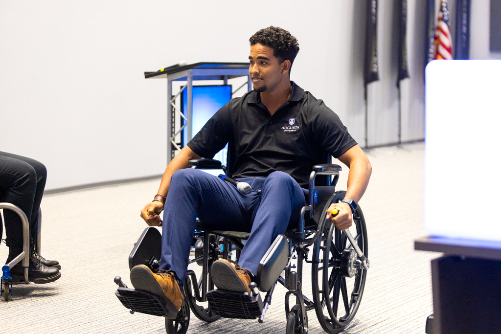 A student shows off a wheelchair with special handles during a pitch presentation.