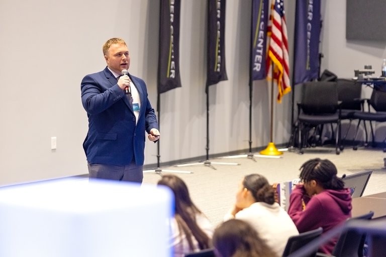 A student talks in front of others in an auditorium.